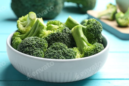 Preview: Bowl of fresh green broccoli on blue wooden table, closeup view