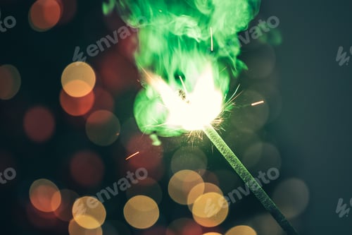 Preview: Close-up of green holiday sparkler in the dark