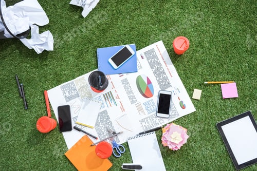 Preview: heap of business objects and office supplies laying on green grass carpet at office, business