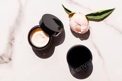 Preview: An open dark glass jar with a cosmetic self-care product on a marble white background