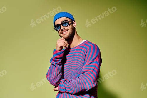Preview: Handsome young man showcases vibrant fashion sense in trendy studio setting