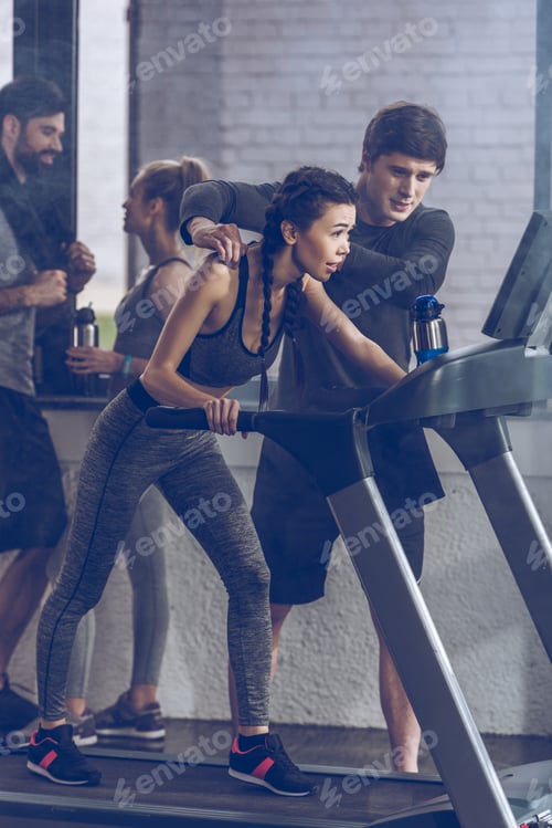Preview: athletic young sportswoman running on treadmill at the gym, fitness couple gym concept