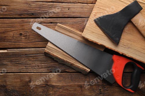 Preview: Saw with colorful handle, axe and logs on wooden background, flat lay. Space for text