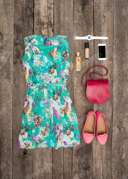 Preview: Colorful floral dress and accessories arranged on wooden surface for summer outfit inspiration