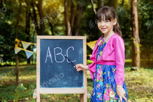 Preview: Little schoolgirl teaches the alphabet near the blackboard. Back to school. The concept of education