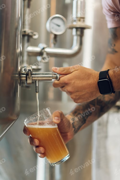 Preview: Close shot of a man filling glass of beer on a tap in brewery