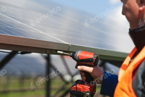 Preview: Close-up view of engineer who tightens the bolts of solar panels to a metal base with electric drill
