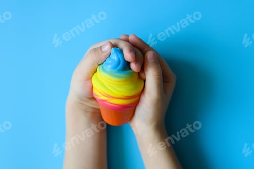 Preview: anti stress squishy toy in the form of multicolored ice cream in children's hands on blue background