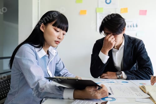 Preview: Team analyzing documents while sitting on a table in office. Woman executives at work in office