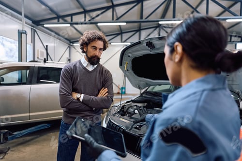 Preview: Mature man talking to female mechanic in auto repair shop.