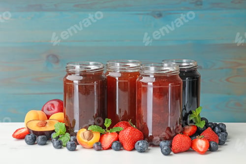 Preview: Different jams in jars and ingredients on white table. Space for text