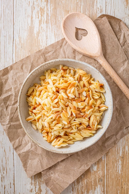 Preview: Cooked italian pasta, risoni, orzo in a bowl on wooden table