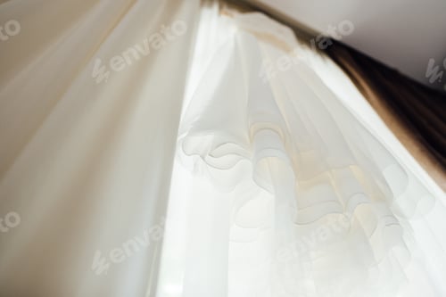 Preview: Elegant Wedding Dress Hanging in a Bright Room