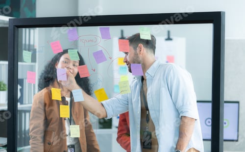 Preview: Multiethnic young business people brainstorming on a project by writing on the glass wall