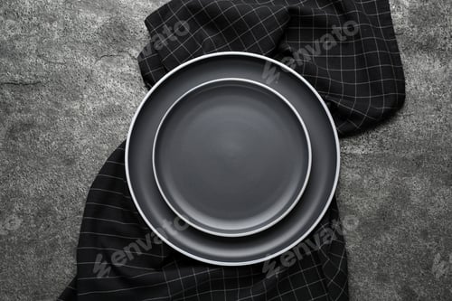 Preview: New dark plates and napkin on grey table, top view