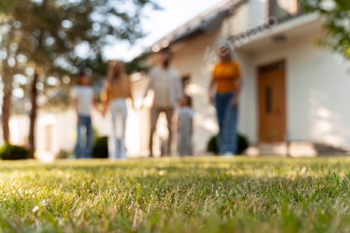 Preview: Family standing in front of their house with green lawn in focus