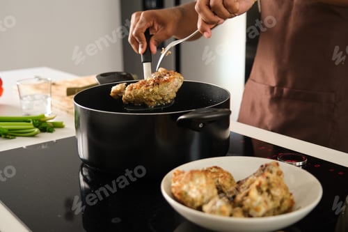 Preview: Unrecognizable young african man preparing fried chicken mince with vegetables.