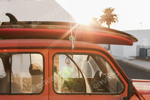 Preview: A stack of surfboards on a retro car roof with sun shining. Summer and surf background wallpaper.