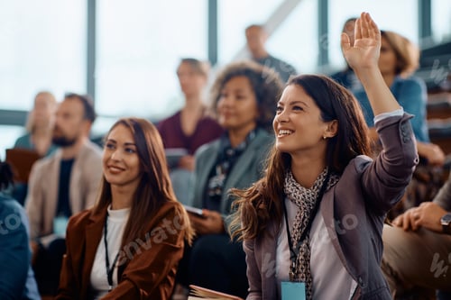 Preview: Happy entrepreneur raising her hand to answer question on business conference in convention center.