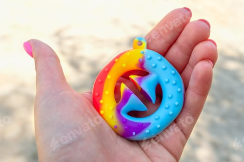 Preview: Snapperz - colorful rubber antistress toy expander in the hand. Close-up.