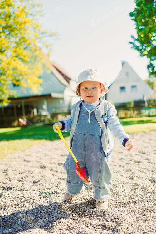 Preview: Toddler playing with a shovel in the sandbox on the playground. Boy playing in nature. 2 year old