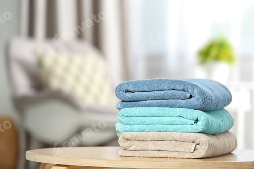 Preview: Stack of folded clean soft towels on table indoors. Space for text