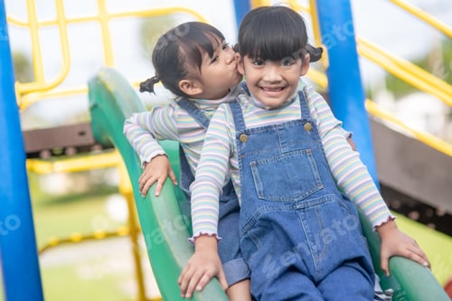 Preview: Cute little girls siblings having fun on playground outdoors on a sunny summer day.