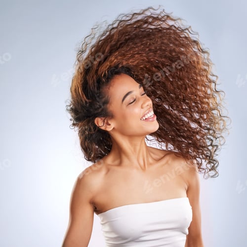 Vista previa: Cropped shot of an attractive young woman whipping her hair in studio against a grey background