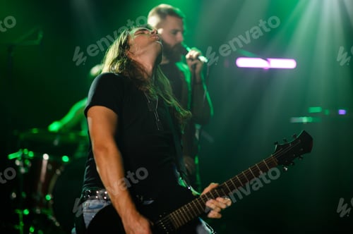 Preview: Guitarist and singer performing on stage with green lights
