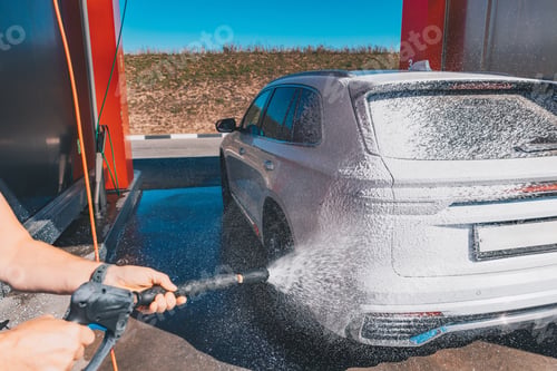 Preview: Сar wash self-service. Man washing luxury vehicle with white foamy detergent.