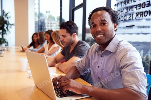 Preview: Portrait Of Businessman Working At Desk In Shared Open Plan Office Workspace