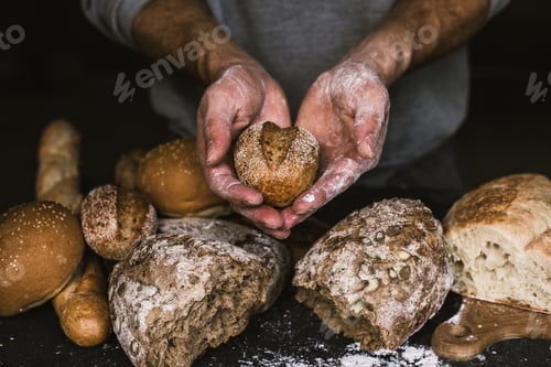 Preview: Baker man holding a rustic organic loaf of bread in his hands
