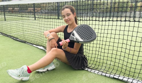Preview: Sportive young girl with racquet playing padel in the open court outdoors