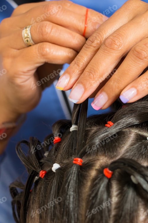 Preview: photography of a hairstyling procedure in the beauty salon. woman making hair braids to a little gir