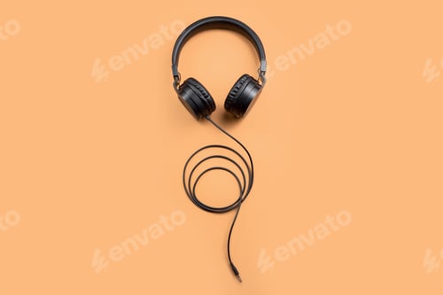 Preview: Photo of stylish modern black headphones over beige background.