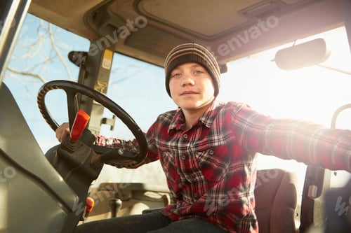 Preview: Portrait of boy farmer driving tractor on dairy farm