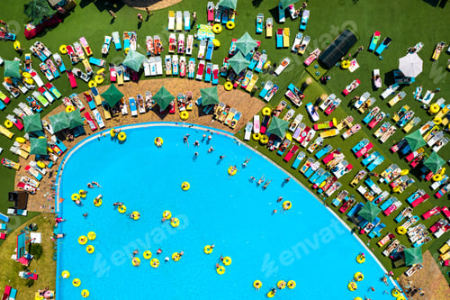Preview: Top view of people relaxing in the pool on yellow inflatable circles and sun beds on the beach