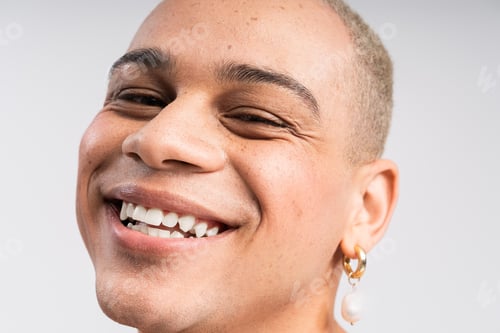 Preview: Stylish man exudes confidence with a charming smile and unique fashion choices in bright lighting
