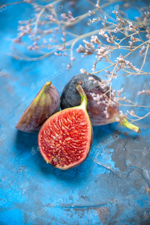 Preview: Top view of split and full fresh black mission figs on blue background image