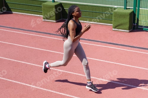 Preview: Sportive African American woman runs on red track around stadium to prepare for upcoming marathon