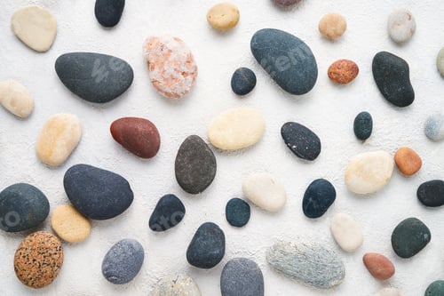 Preview: Set of colorful sea stones on white concrete backdrop. Top view, abstract background