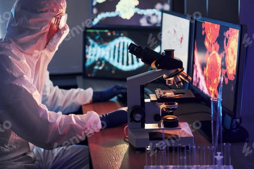 Preview: Scientist in white protective uniform works with coronavirus and blood tubes in laboratory