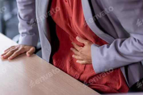 Preview: Stomach ache, sick business woman holding hands on stomach close up, female worker at workplace