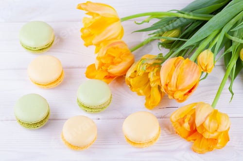 Preview: pastries macarons and yellow tulips on white wooden background