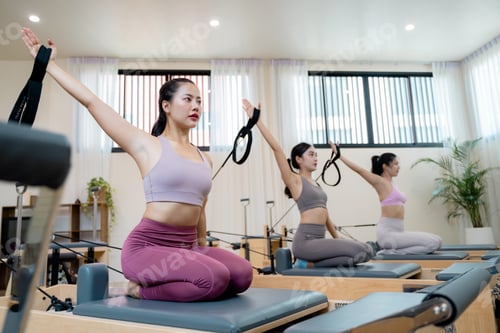 Preview: Asian women practicing pilates with reformer beds in a gym