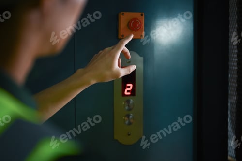 Preview: Cropped shot of male worker pressing elevator button in warehouse. Industrial workers concept