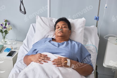 Preview: Black senior woman laying on bed in hospital room with IV support