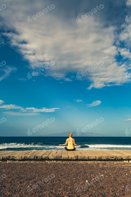 Preview: Yoga girl meditating and relaxing in yoga pose, ocean view