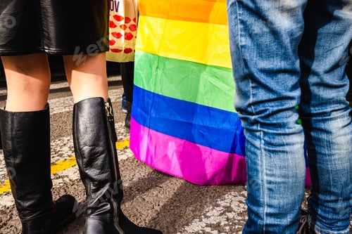 Preview: Legs of women walking in an LGBT demonstration between rainbow flags.