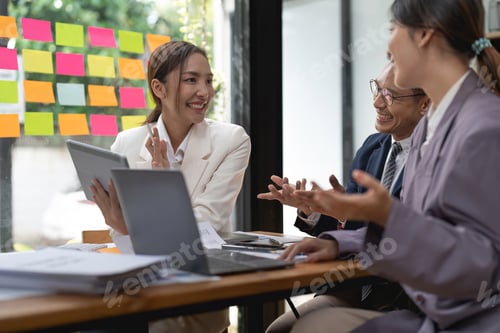 Preview: Group of young business people working and communicating while sitting at the office desk together